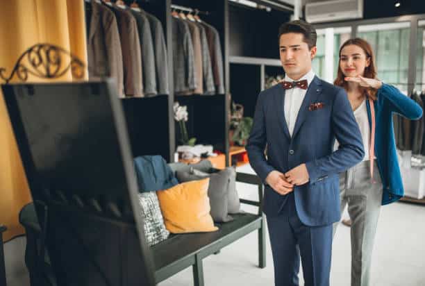 Homme essayant un costume sur mesure avec une couturière ajustant le col.